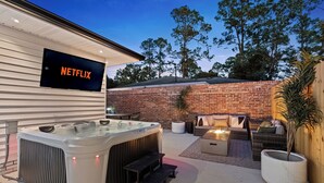 Eine moderne Außenpatio mit Whirlpool, Sitzgelegenheit und einem Netflix-Schild an der Wand.