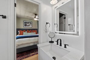 A modern bathroom with a white sink, black faucet, and a large mirror. - Luxury 6 bedroom compound 5 min from Masters, Putting, Hot Tubs, Fire Pits, EVs (Augusta)