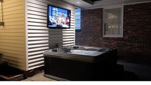 Ein Whirlpool vor einem Haus, an der Wand ist ein Fernseher angebracht.