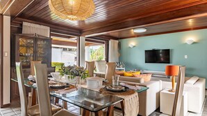 A dining area with a glass table, chairs, and a hanging light fixture.