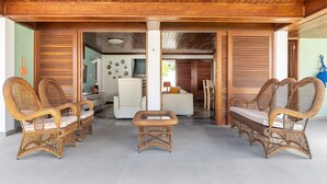 A covered outdoor seating area with wicker furniture, a white sofa, and a small table.