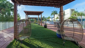 Un espacio al aire libre cubierto con dos sillas de mimbre, una pérgola y un césped bien cuidado.