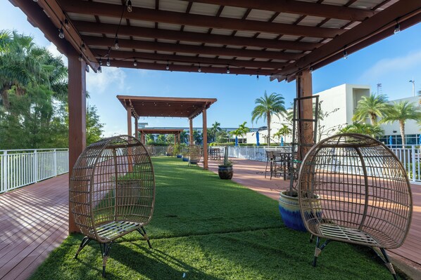 A covered outdoor area with two wicker chairs, a pergola, and a well-maintained lawn. - Luxury Spot / Game room / Pool / Cinema / Spa / Downtown access (Fort Myers)