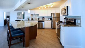 A modern kitchen with a central island, stainless steel appliances, and pendant lighting. - Relax in Style: 2BR Ocean View Condo at Atlantic Terrace (Daytona Beach)