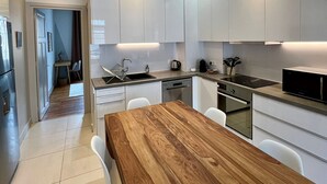 A modern kitchen with white cabinets, a wooden dining table, and white chairs.