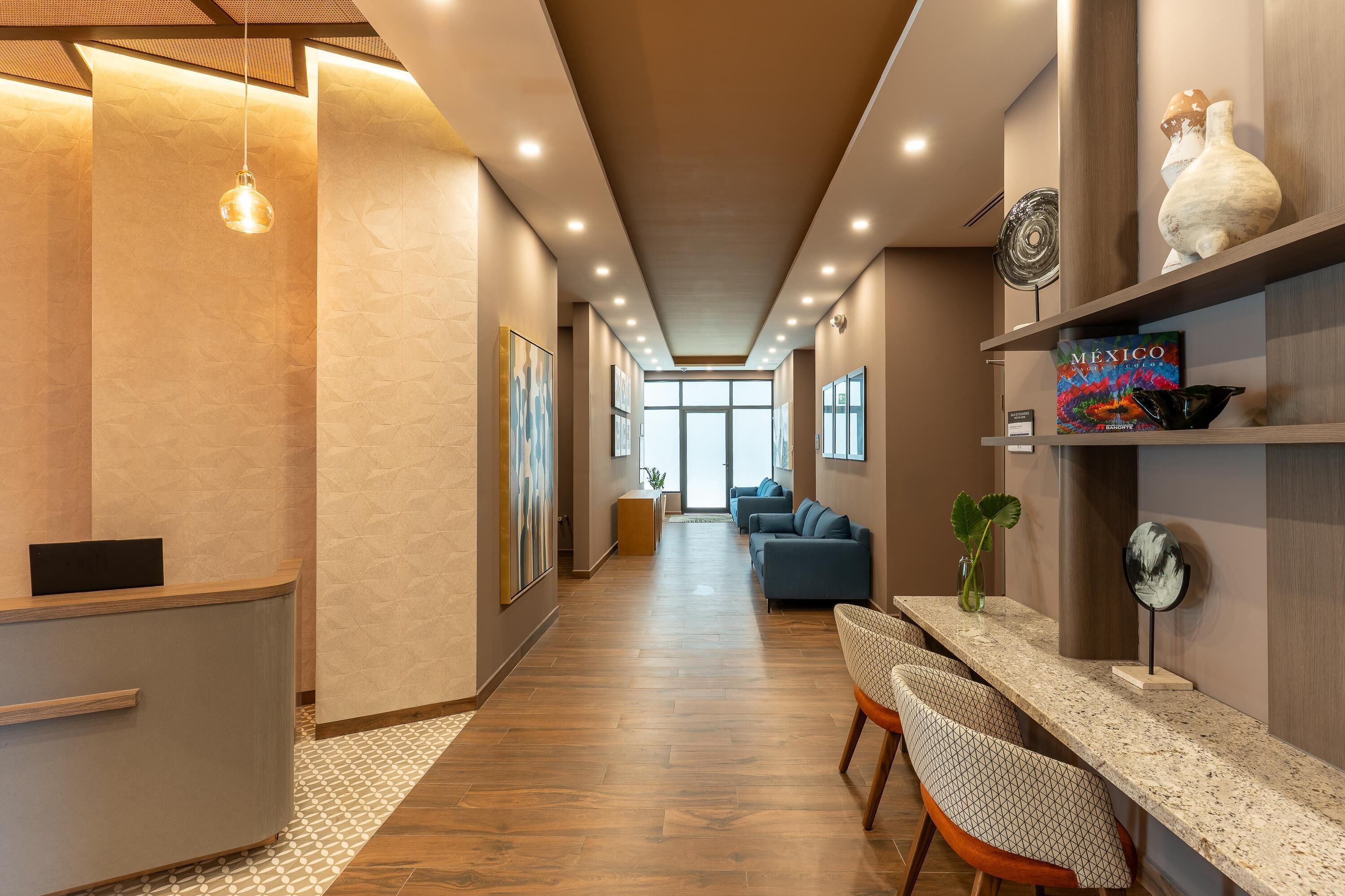 A modern hotel lobby with a reception desk, seating area, and a view to the dining area.