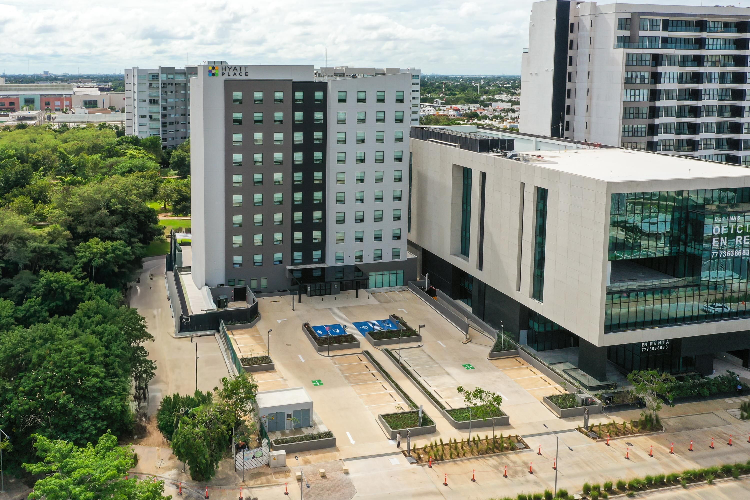 A modern hotel with a central courtyard, multiple parking spaces, and a large glass facade.