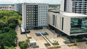 Un hotel moderno con un patio central, múltiples espacios de estacionamiento y un amplio frente de vidrio.