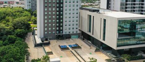 A modern hotel with a central courtyard, multiple parking spaces, and a large glass facade.