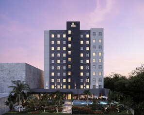 A multi-story hotel with a modern design, featuring a prominent logo at the top.