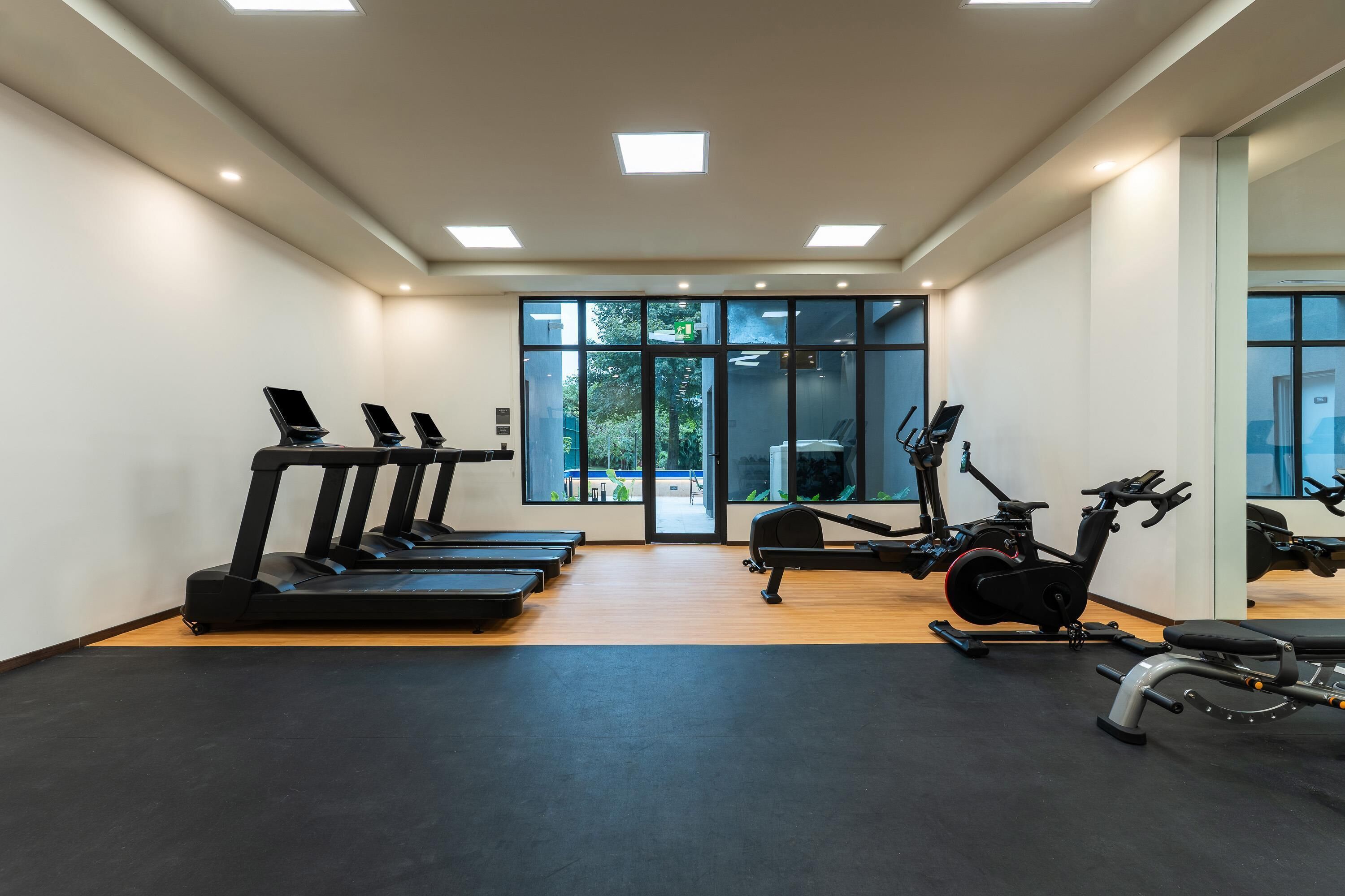 Un gimnasio con cintas de correr, una elíptica y una bicicleta estática.