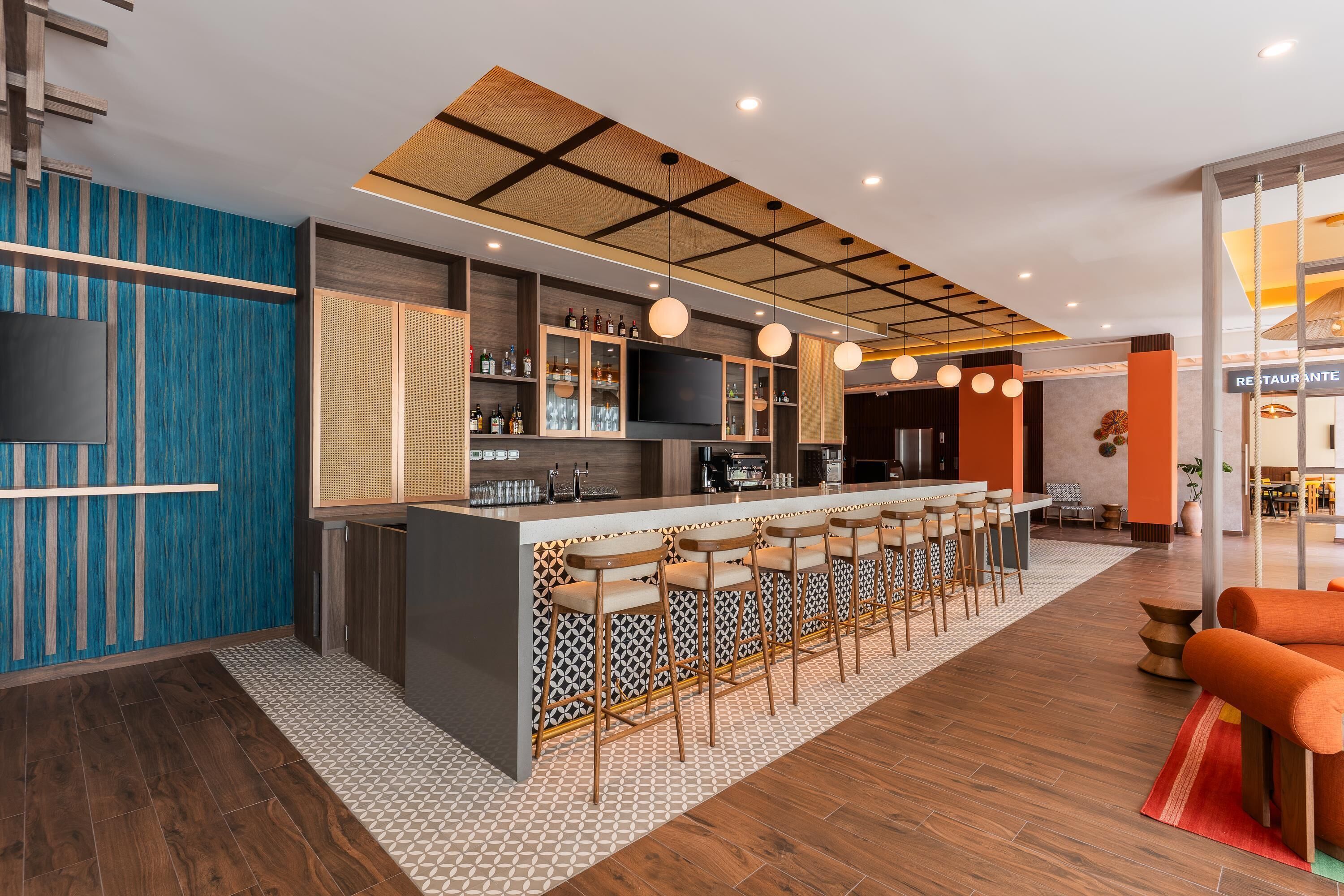 Un bar moderno con una barra larga, taburetes y un televisor.