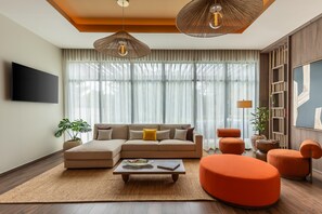 A modern living room with a sectional sofa, a coffee table, and orange ottomans.