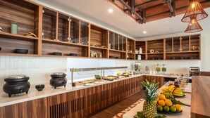 A modern kitchen with wooden cabinets, a long counter, and a fruit display. - Hyatt Place Merida/Via Montejo (Mérida)