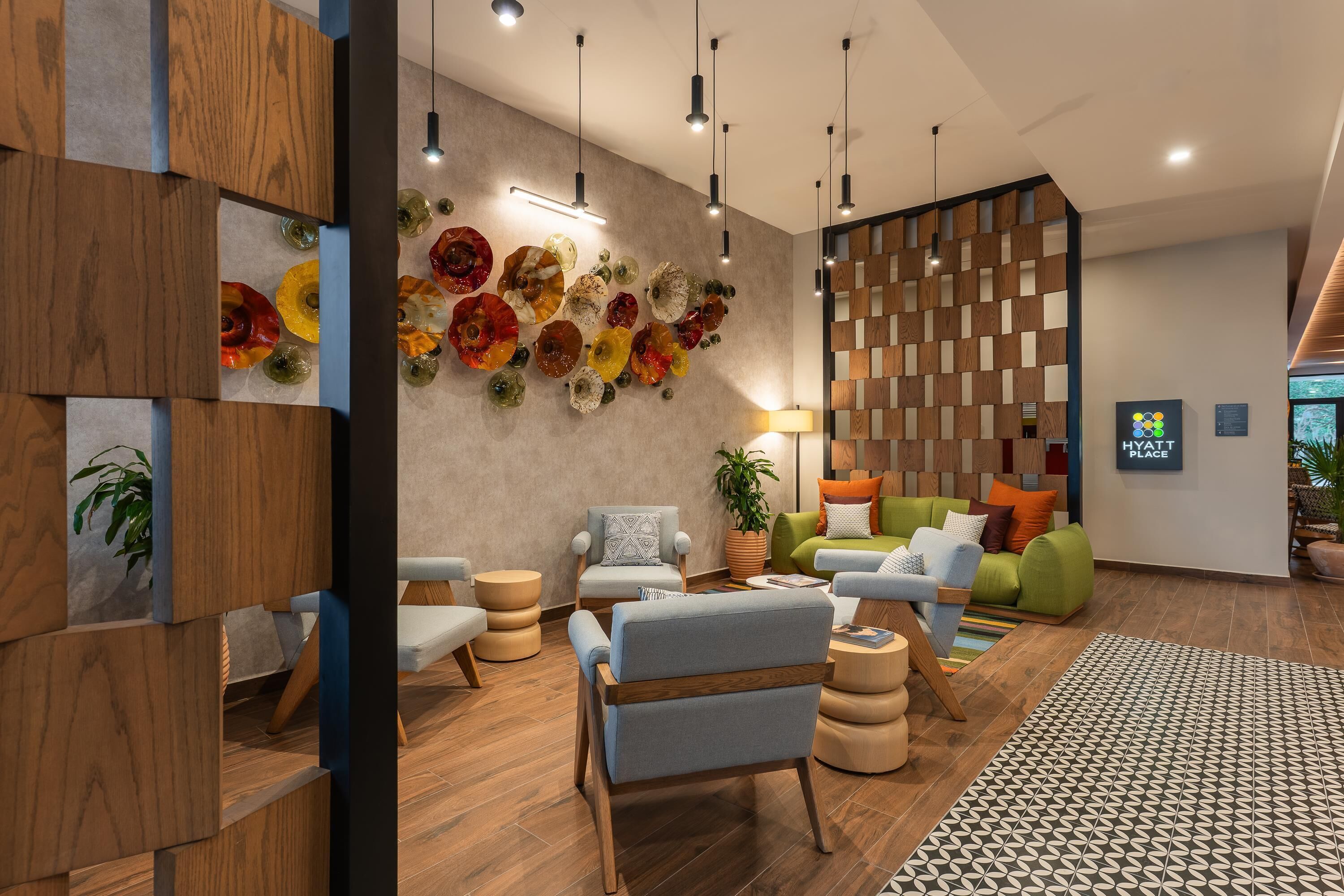 A modern hotel lobby with wooden accents, a floral wall art, and a variety of seating options.