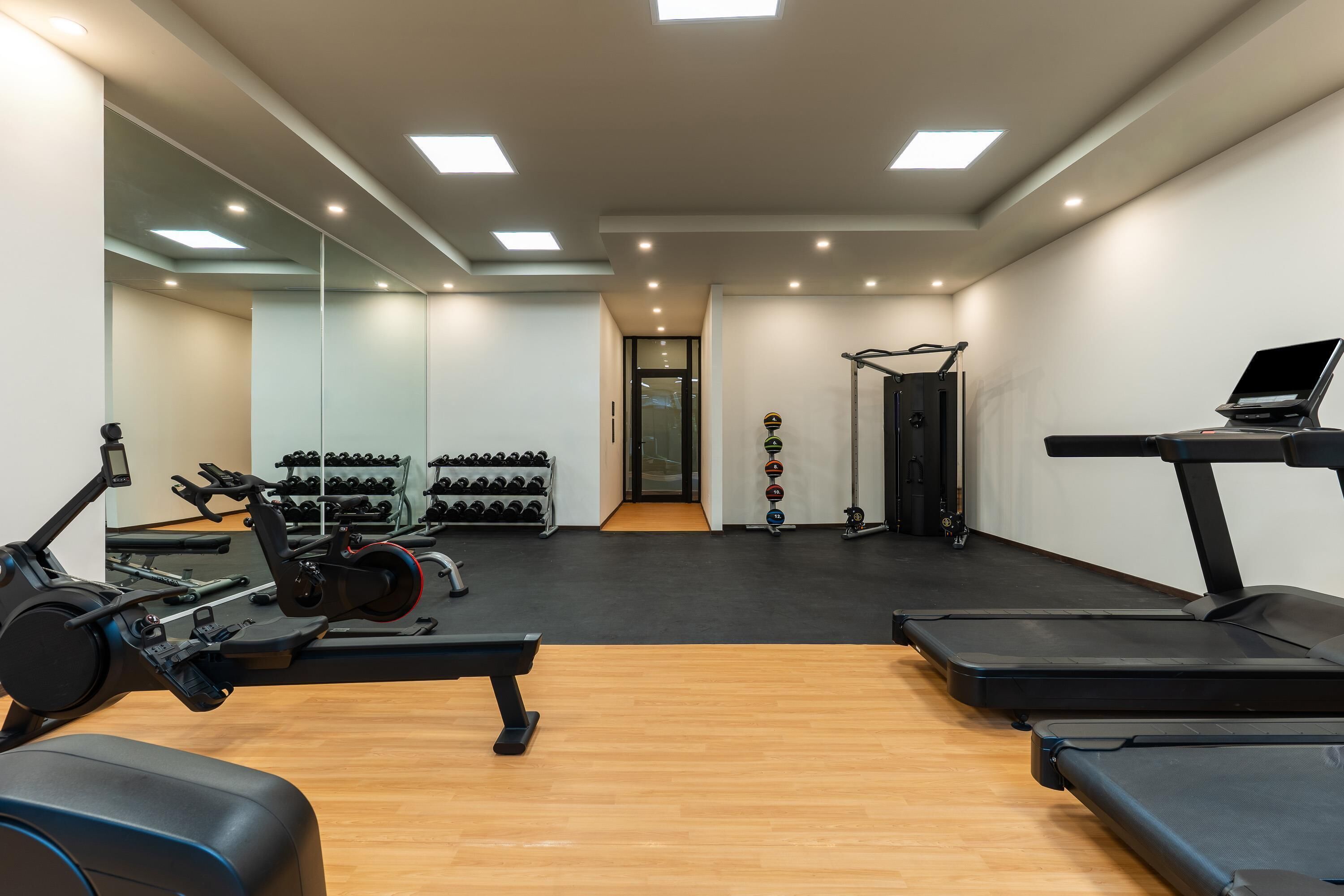 A modern gym with cardio equipment, weight racks, and a treadmill.