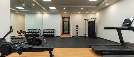 Un gimnasio con equipo cardiovascular, máquinas de pesas y mancuernas.