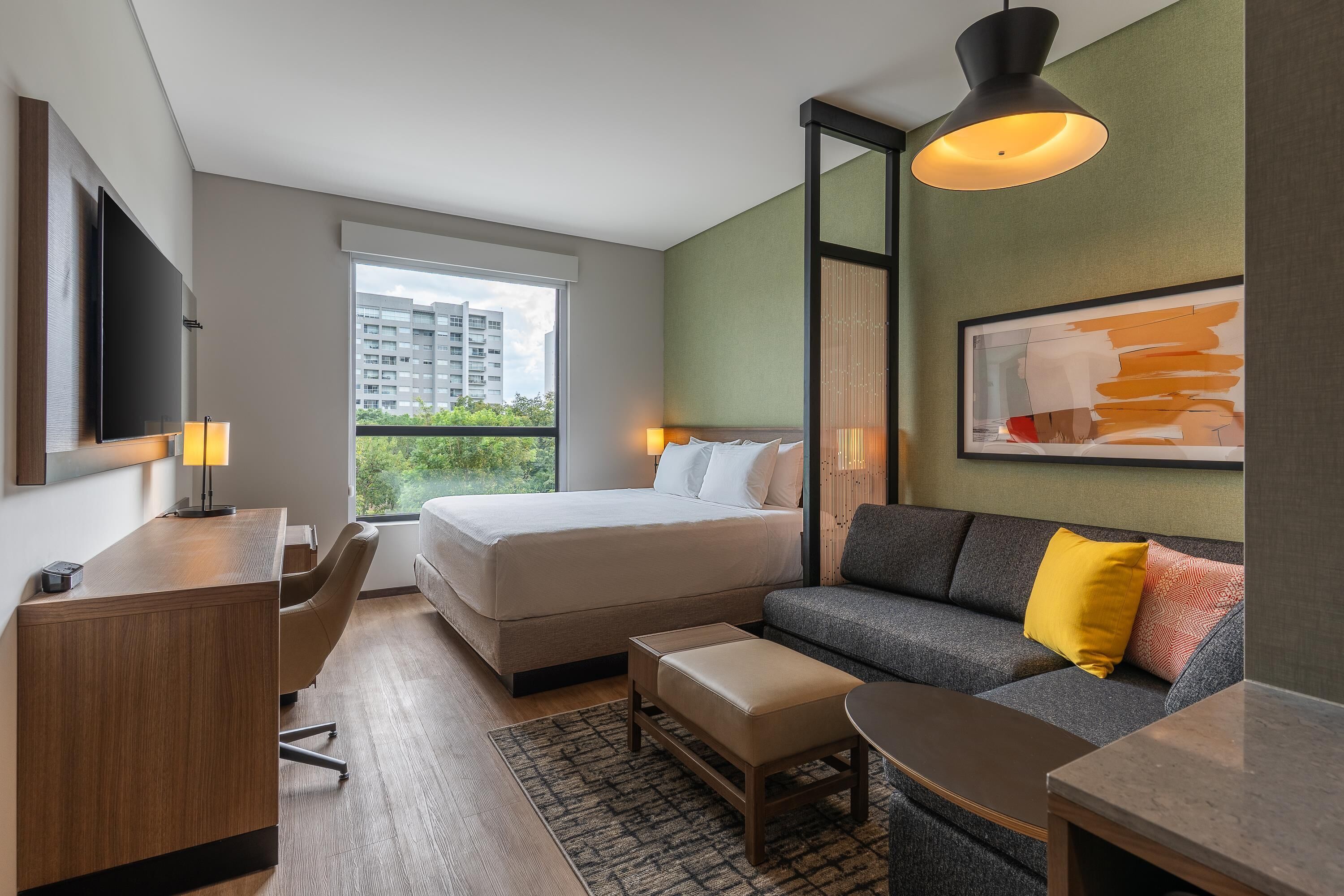 Una habitación de hotel moderna con una cama grande, un sofá, un escritorio y un televisor.
