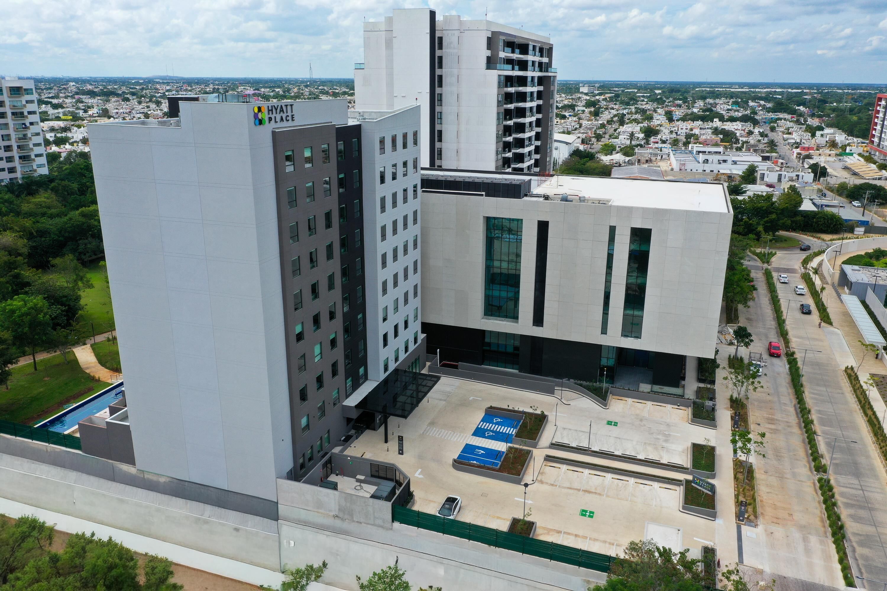 A modern hotel with a rooftop pool, surrounded by other buildings.