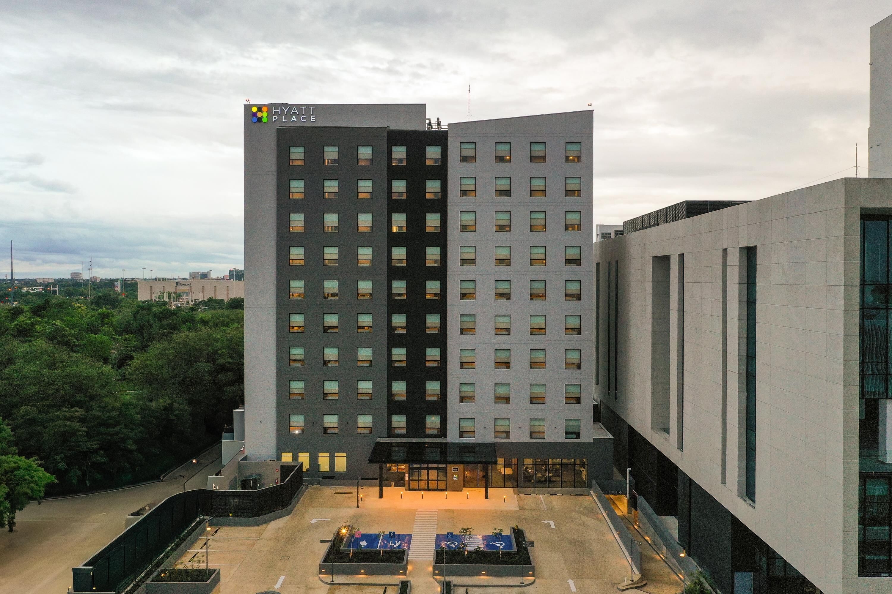 A modern hotel building with a flat roof, multiple floors, and a prominent entrance with glass doors.