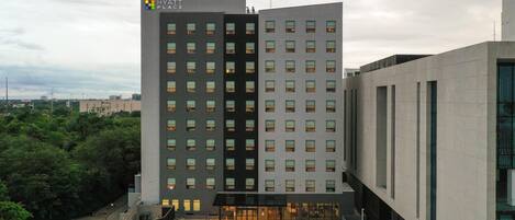 A modern hotel building with a flat roof, multiple floors, and a prominent entrance with glass doors.