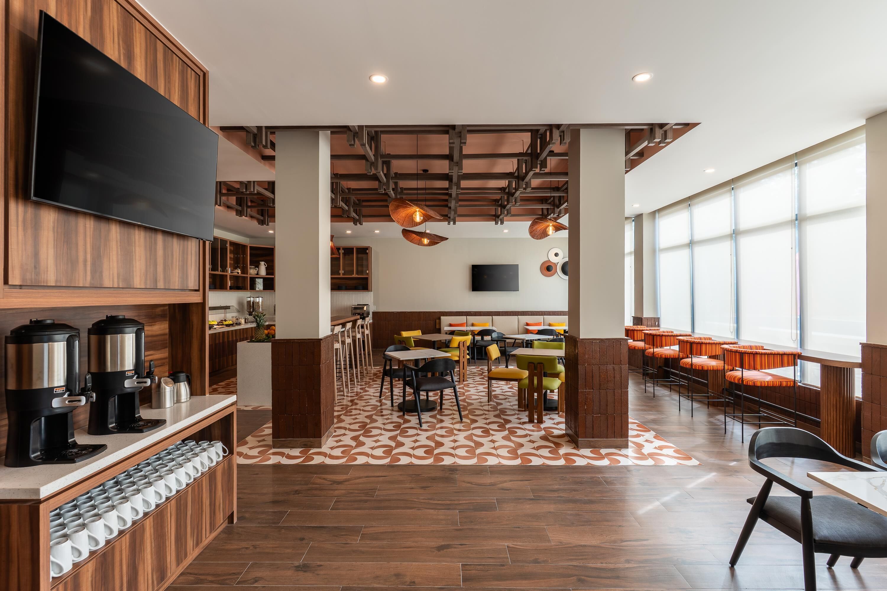 Un restaurant moderne doté d’un espace de restauration central, d’un coin café et d’une grande fenêtre laissant entrer la lumière naturelle.