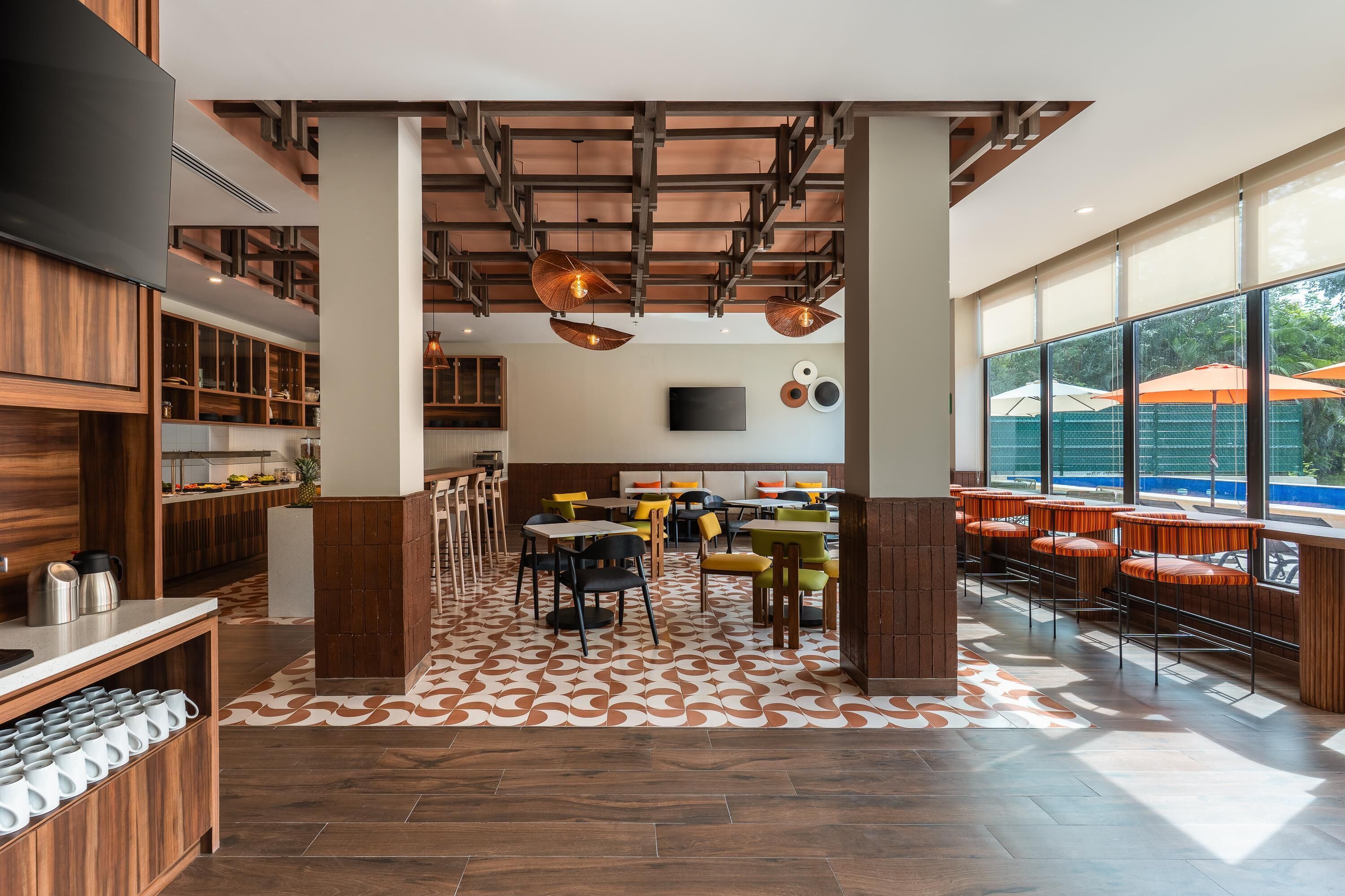 A modern restaurant with a central seating area, wooden accents, and large windows offering a view of the outdoors.