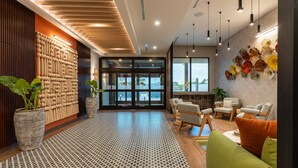 A modern lobby with a wooden reception desk, seating area, and large windows. - Hyatt Place Merida/Via Montejo (Mérida)