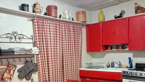 A kitchen with red cabinets, a wooden table, and a checkered curtain. - Studio apt in the heart of town. (Lake City)