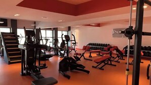 Un gimnasio con diversos equipos de ejercicio, incluyendo cintas de correr, máquinas de pesas y mancuernas.