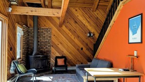 Un interior acogedor con chimenea, vigas de madera, un sofá y una mesa.