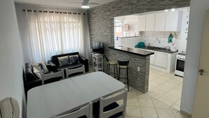 A modern kitchen with white cabinets, a grey backsplash, and a small island.