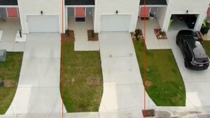 Une rangée de maisons à deux étages, chacune avec un garage attenant, une allée et une pelouse.