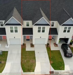 A row of two-story houses with attached garages, a driveway, and a lawn.