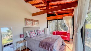 Une chambre avec un grand lit, un canapé rouge, une fenêtre avec des rideaux et une vue sur l’extérieur.