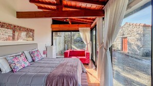 Une chambre à coucher avec un lit, un canapé rouge et un mur en pierre à l’extérieur.