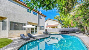 Ein modernes Haus mit Swimmingpool, Gartenmöbeln und einem gepflegten Rasen.