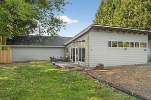 Et moderne hus med to etager, en patio og et overdækket udendørs siddeområde.