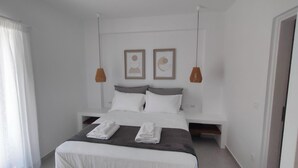 A modern bedroom with a bed, two bedside tables, and two pendant lights.