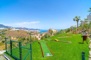Un parcours de golf offrant une vue sur la mer et les montagnes.