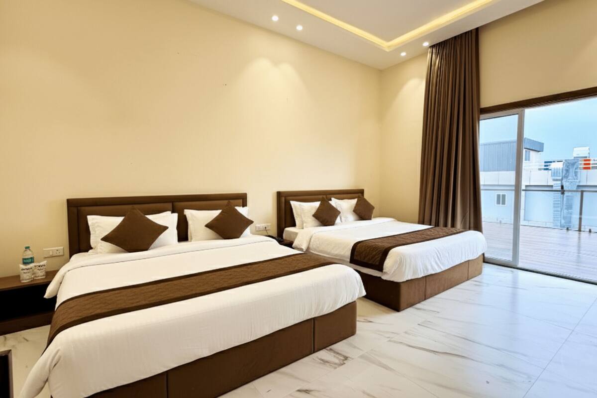 A hotel room with two beds, a large window, and a view of the city.