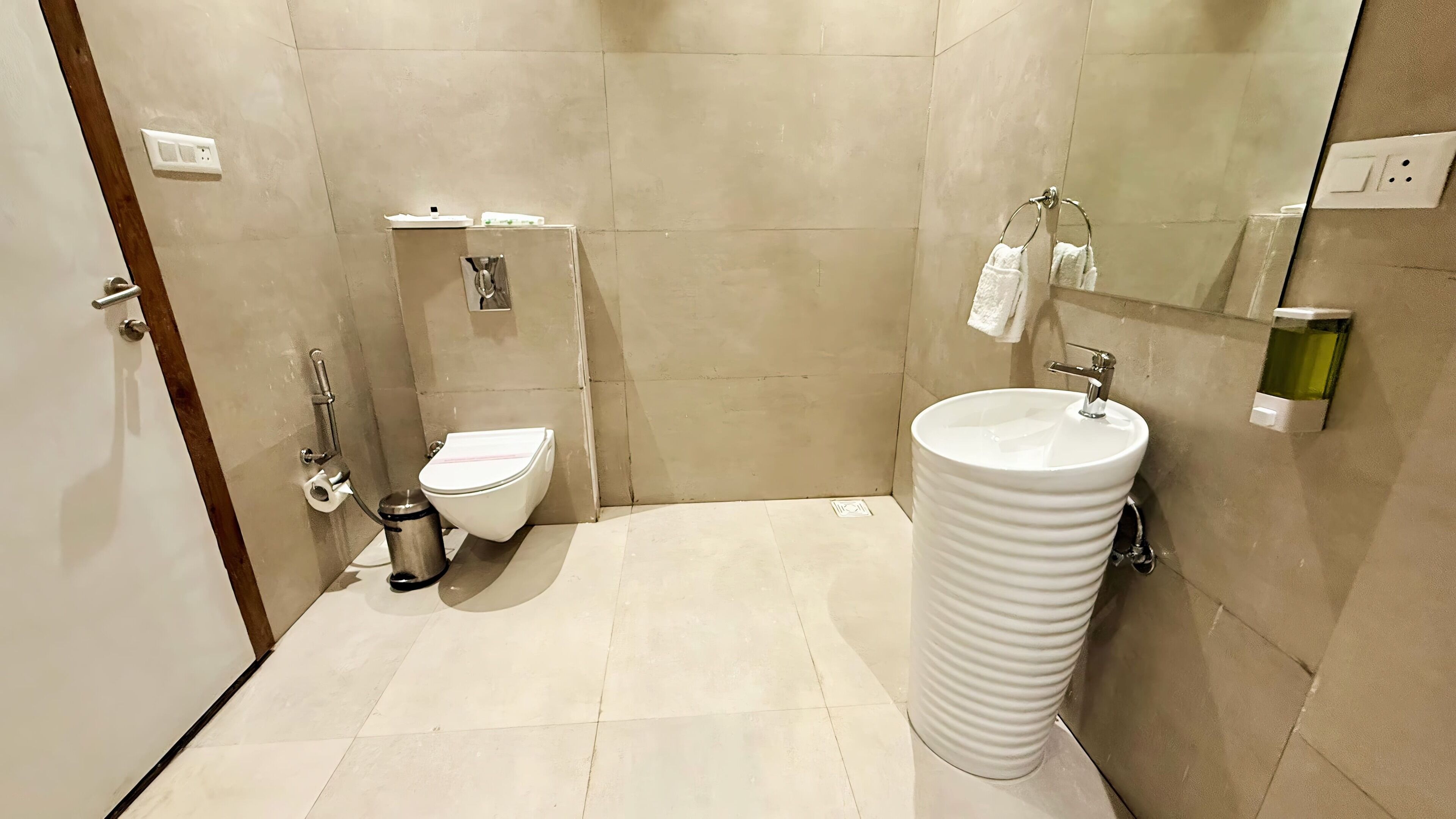 Un baño pequeño y moderno con inodoro, lavamanos y espejo.