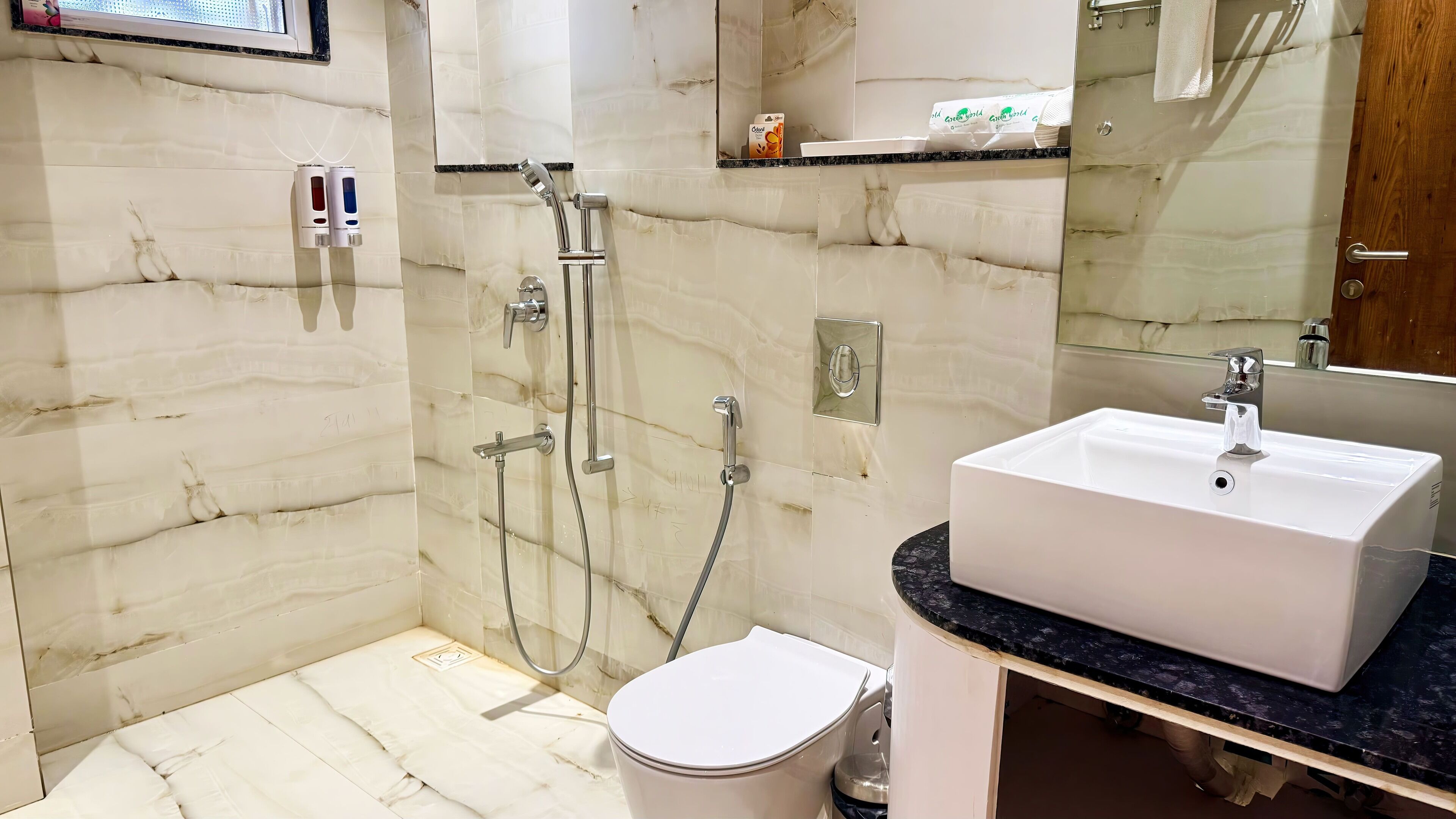 A modern bathroom with a white sink, a glass-enclosed shower, and marble walls.