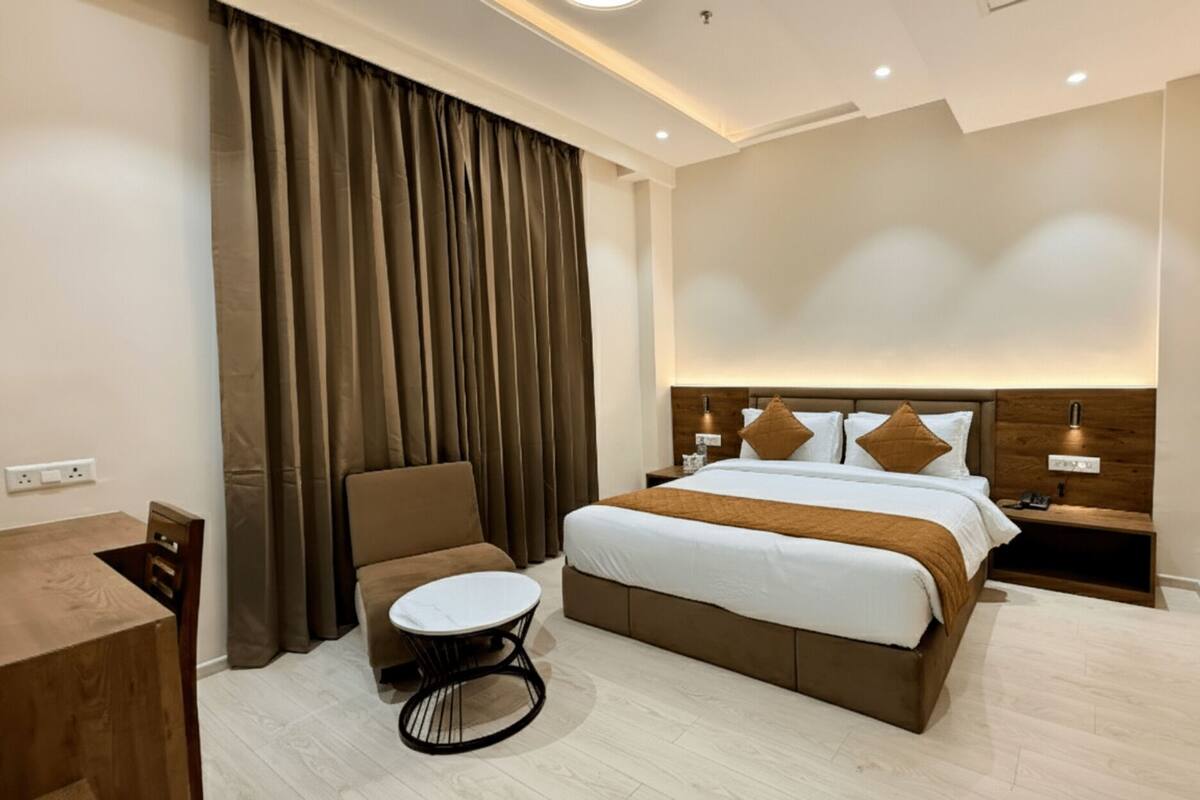 A modern hotel room with a large bed, a round table, and a chair.