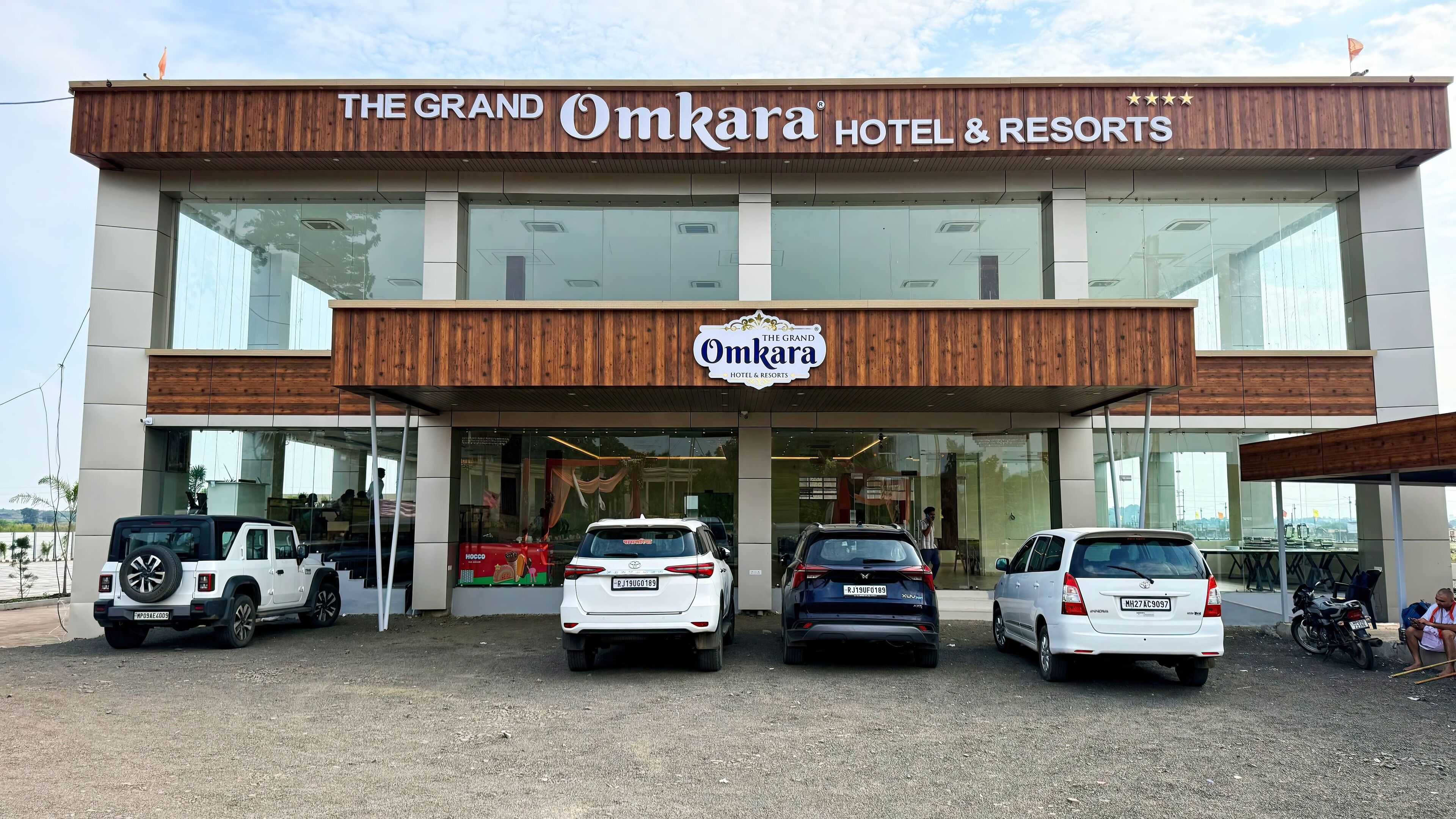 The Grand Omkara Hotel & Resorts with a modern facade, large glass windows, and a prominent sign.