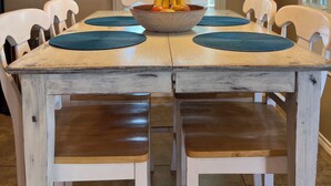 A dining table with a bowl of fruit and placemats, surrounded by white chairs. - Spacious 3BR Home • Sleeps 6 • Open Living • Private Yard (Victoria)