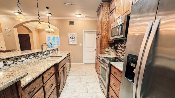 A kitchen with wooden cabinets, a stainless steel refrigerator, a microwave, and a sink. - Spacious 3BR Home • Sleeps 6 • Open Living • Private Yard (Victoria)