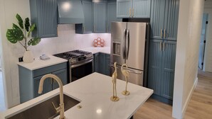 Eine moderne Küche mit blauen Schränken, einem Edelstahlkühlschrank und einer weißen Arbeitsplatte.