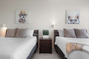 Ein Schlafzimmer mit zwei Betten, einem Nachttisch mit Pflanze und Bildern an den Wänden.