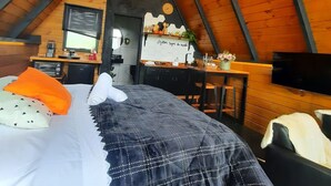 Une chambre mansardée chaleureuse, avec un lit, un bureau, une télévision et un lustre.